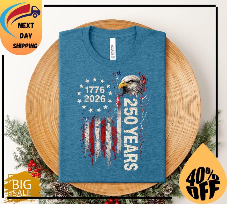 Pode incluir: Uma camiseta azul com um design desgastado da bandeira americana, uma &aacute;guia e o texto "1776 2026 250 YEARS". A camisa &eacute; feita de um material macio.