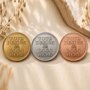 May include: Three circular metal medallions in gold, silver, and copper tones. Each medallion features a raised border and the embossed text YOUR DESIGN OR LOGO HERE centered on the face. The items are arranged horizontally in a row.