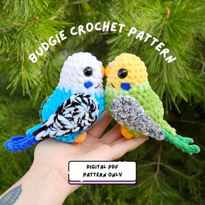May include: Two plush crochet budgie birds, one white and blue with black and white wings, the other yellow and green with grey and white wings. Text reads: BUDGIE CROCHET PATTERN and DIGITAL PDF PATTERN ONLY. These are soft, stuffed yarn toys.
