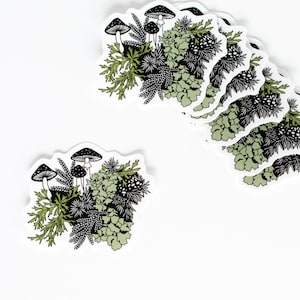 May include: A set of eight stickers featuring a black and white illustration of mushrooms and greenery. The stickers are white with a rounded shape.
