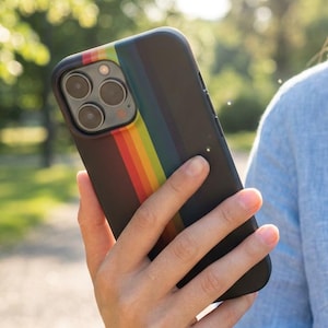 Puede incluir: Una funda de smartphone negra con un patrón de rayas verticales de arcoíris a lo largo del módulo de la cámara. La funda tiene un acabado mate y un recorte para el sistema de cámara de triple lente en la parte posterior del dispositivo.