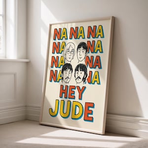 Puede incluir: Una impresión artística enmarcada con las palabras "NA NA NA NA HEY JUDE" en letras naranjas, amarillas y azules. La obra de arte presenta retratos de dibujos animados de cuatro hombres. El fondo es de color crema.