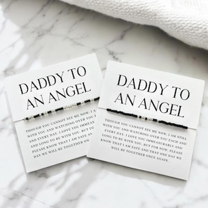May include: Two white cards with the text "DADDY TO AN ANGEL" and a beaded bracelet. The cards have a message about love and remembrance. The bracelets have black and silver beads.
