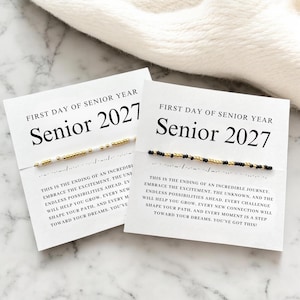May include: Two white cards with the text "FIRST DAY OF SENIOR YEAR" and "Senior 2027". Each card features a bracelet with gold, black, and white beads. The cards also have inspirational text about embracing the future.