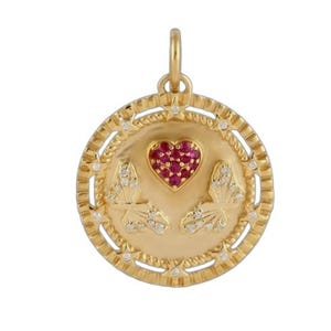 May include: A gold-colored pendant with a heart-shaped ruby center and two butterfly designs. The pendant has a decorative border with small, clear gemstones. The bail is also gold-colored.