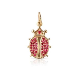 May include: A gold-colored ladybug charm with a loop for hanging. The ladybug's body is covered in small, round, red gemstones. The charm has six small legs and a detailed head.