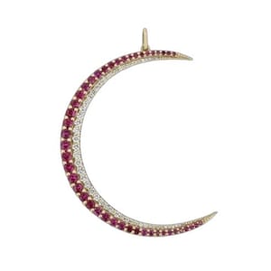 May include: A gold-coloured crescent moon pendant, featuring a bail for hanging. The moon is adorned with alternating rows of small, round, red and white gemstones. The pendant is set against a white background.