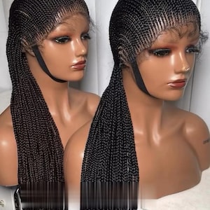 May include: Two black braided wigs on mannequin heads. The wigs have detailed cornrow patterns and long, flowing braids. The lace fronts are visible, and the wigs are secured with black straps. The mannequins have tan skin tones.