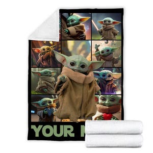 May include: A plush, white blanket featuring a collage of images of a green alien character with large ears, wearing a brown cloak. The blanket has a black border and the text "YOUR" at the bottom.