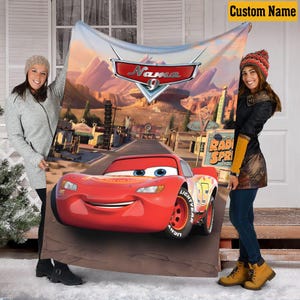 May include: A red Cars-themed blanket featuring Lightning McQueen on a desert road with the text "Name 9" and "Radiator Springs". The blanket has a custom name banner in the top right corner.