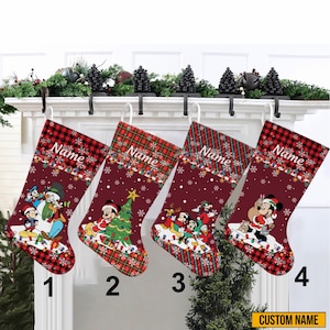 May include: Four Christmas stockings with a burgundy background and a red and black plaid cuff. Each stocking features a different Disney character scene, with the word "Name" printed on the cuff. The stockings are numbered 1 through 4.