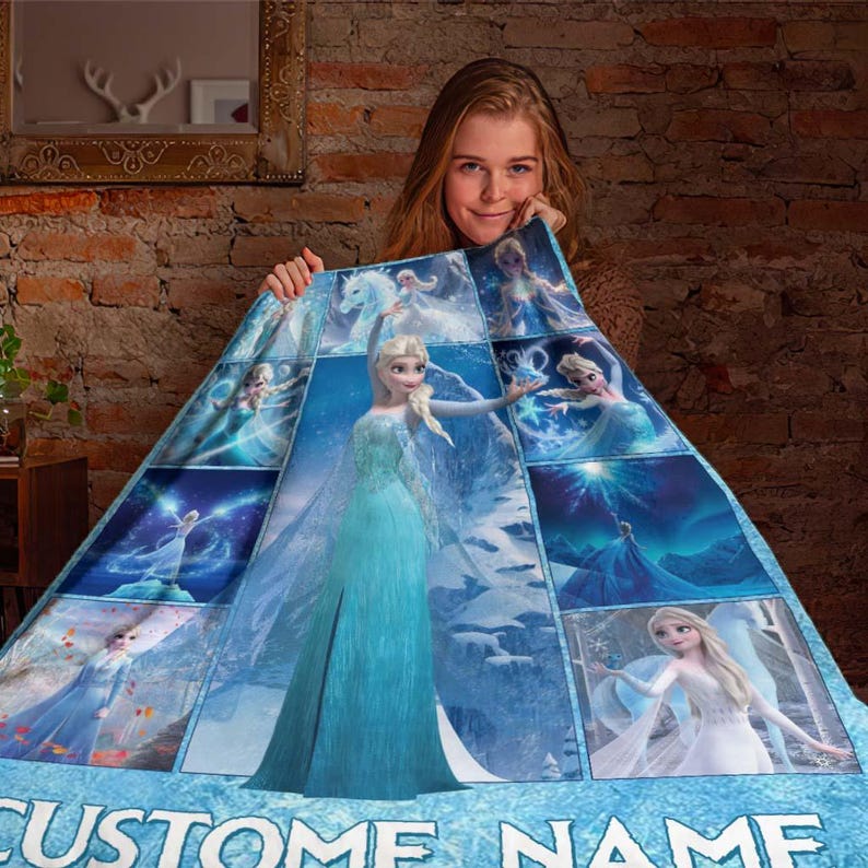 May include: A blue and white blanket featuring images of a princess in a blue dress. The blanket has a collage design with the words "CUSTOM NAME" at the bottom. The blanket is held up by a person.
