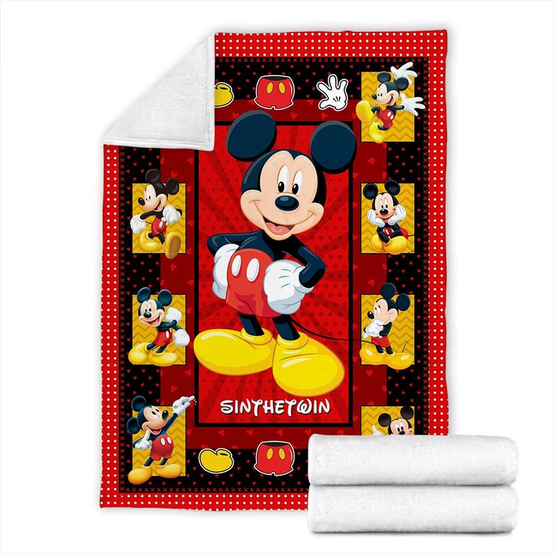May include: A red and black Mickey Mouse themed blanket. The blanket features a large image of Mickey Mouse in the center, surrounded by smaller images of Mickey. The border is red with black polka dots. The blanket is folded with two white blankets.