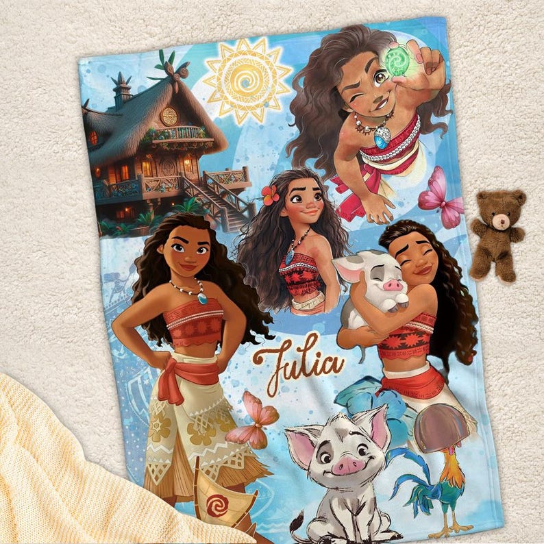 May include: A soft blanket featuring a colorful print of the character Moana in various poses, a tropical hut, a piglet, a rooster, and a butterfly. The name Julia is written in a brown script font in the center of the blue-toned design.