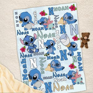 Może przedstawiać: Jasnoniebieski kocyk dla dziecka z postacią Stitch z Lilo & Stitch. Kocyk ma wiele obraz&oacute;w Stitcha, imię "Noah", literę "N" i czerwone kwiaty hibiskusa. Mały brązowy miś pluszowy leży obok kocyka.