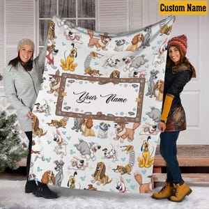 May include: A white blanket featuring various cartoon dog illustrations. The blanket has a brown frame with the text "Your Name" in the center. The blanket is held by two people.