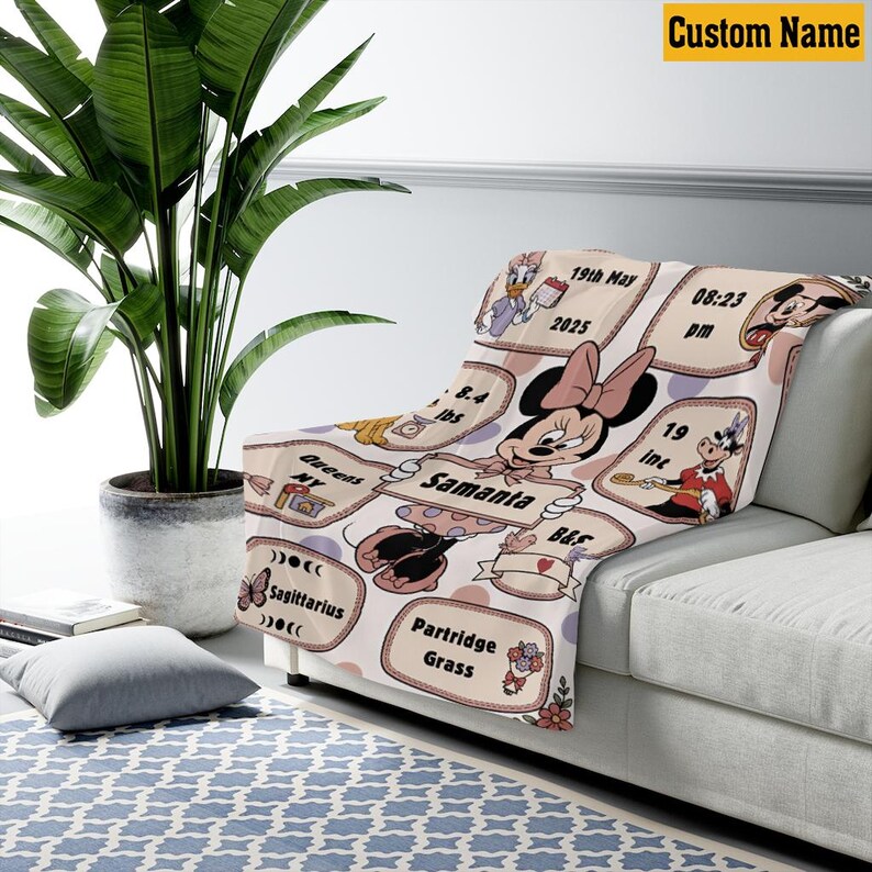 May include: A personalized Minnie Mouse-themed blanket in soft pink. The blanket features Minnie Mouse, along with custom text and birth details. The blanket is draped over a sofa, showcasing its design and size.
