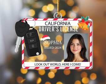 May include: A Christmas ornament shaped like a California driver's license with a photo of a person named Sophia. The ornament includes a car key and the text "LOOK OUT WORLD, HERE I COME!"