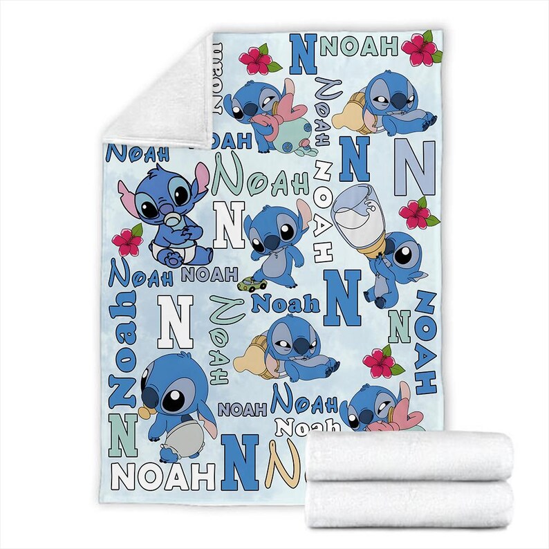 Może przedstawiać: Jasnoniebieski kocyk dla dziecka z postacią Stitch z Lilo & Stitch. Kocyk ma wz&oacute;r ilustracji Stitcha, imię "Noah", literę "N" i czerwone kwiaty. Na dole znajdują się dwa białe, złożone ręczniki.