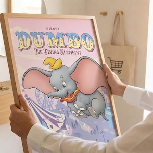 May include: A framed poster featuring the Disney character Dumbo, a gray elephant with large pink ears and a yellow hat. The text reads Disney Dumbo The Flying Elephant. The background shows a circus scene with a Ferris wheel in soft purple tones.