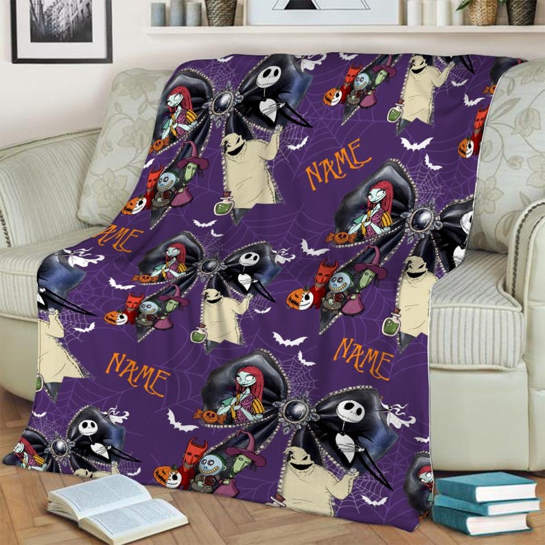 May include: A purple fleece blanket featuring a repeating pattern of black bows, white spiderwebs, and characters from The Nightmare Before Christmas, including Jack Skellington, Sally, and Oogie Boogie, with the word NAME printed in orange.