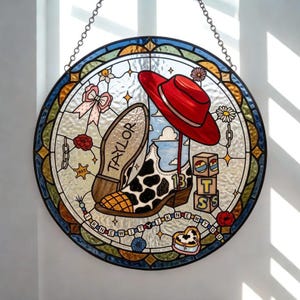 May include: A circular stained glass suncatcher featuring a cow-print cowboy boot with the name TAYLOR on the sole and the number 13 on the side. A red hat, alphabet blocks spelling TSS, a pink bow, and a beaded string with text I KNEW YOU.