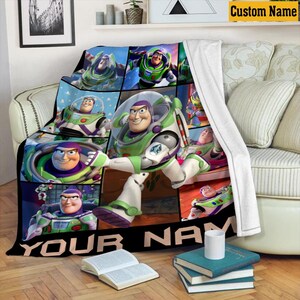 May include: A white-backed fleece blanket featuring a grid of multiple images of the character Buzz Lightyear in his green, white, and purple space ranger suit. The bottom of the blanket includes a black banner with the text YOUR NAME.