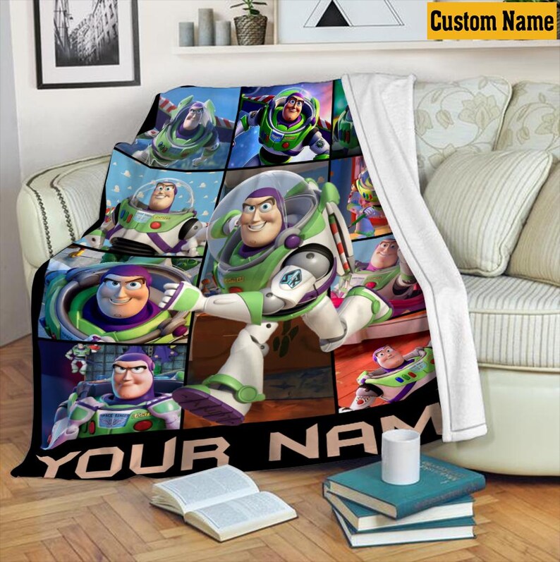 May include: A white-backed fleece blanket featuring a grid of multiple images of the character Buzz Lightyear in his green, white, and purple space ranger suit. The bottom of the blanket includes a black banner with the text YOUR NAME.