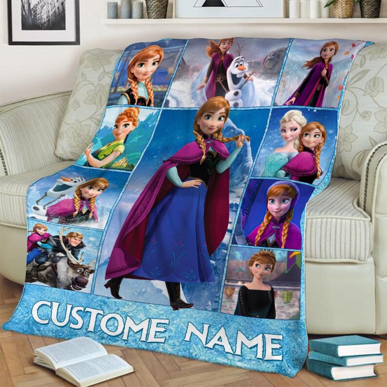 May include: A blue fleece blanket featuring multiple images of characters from the animated film "Frozen." The blanket has a collage design with the text "CUSTOM NAME" in white letters at the bottom. The blanket is draped over a sofa.