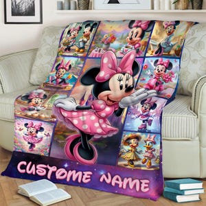 May include: A colorful Minnie Mouse blanket with a collage of images featuring Minnie in various poses and outfits. The blanket is pink, purple, and blue, with the words "CUSTOM NAME" in pink letters across the bottom.