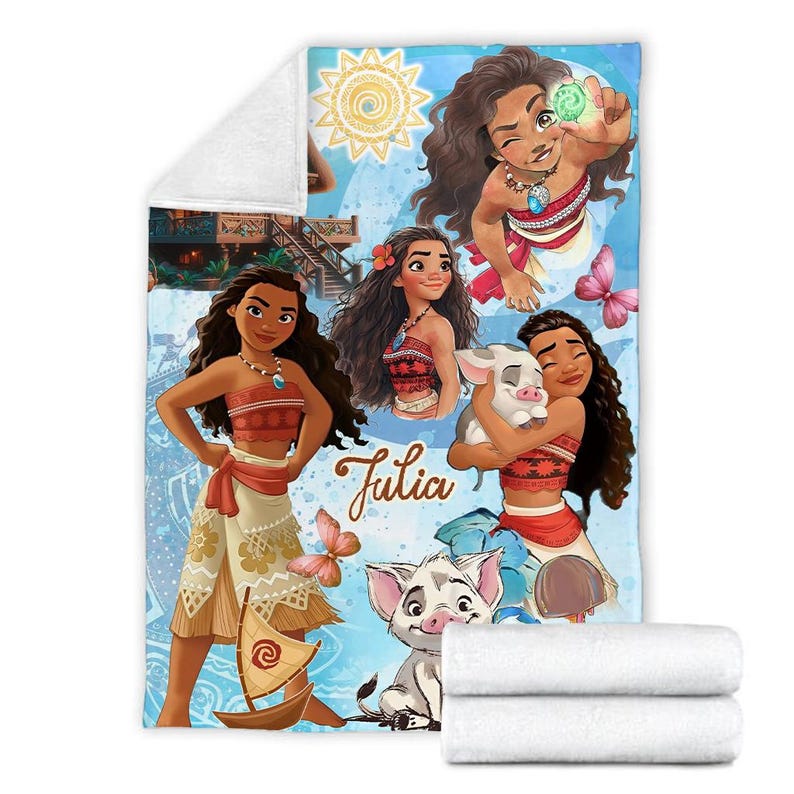May include: A soft fleece blanket featuring a vibrant blue background with multiple illustrations of the character Moana, a small pig, and a sailboat. The name Julia is printed in a brown script font. The design includes a yellow sun and butterflies.
