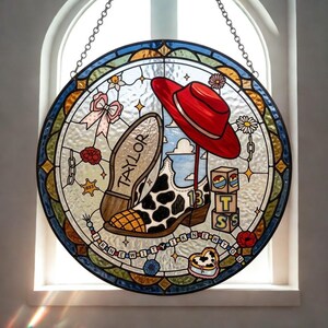 May include: A circular stained glass suncatcher featuring a cow-print cowboy boot with the number 13, a red hat, and blocks labeled T S S. The text TAYLOR is on the boot sole, and a banner reads I KNEW IT I KNEW YOU, surrounded by floral motifs.
