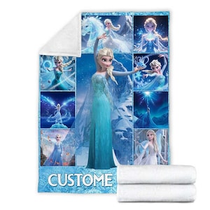 May include: A blue and white blanket featuring multiple images of a blonde princess in a blue dress. The word "CUSTOM" is at the bottom of the blanket. Two white folded towels are at the bottom right.