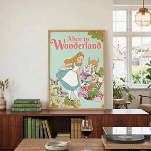 May include: A framed wall art print featuring the text Alice in Wonderland with a light green background. The illustration depicts Alice in a blue dress, the White Rabbit, the Mad Hatter, and the Cheshire Cat surrounded by flowers and butterflies.