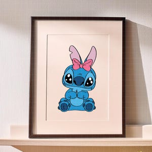 Pu&ograve; includere: Stampa incorniciata con un personaggio dei cartoni animati blu con grandi occhi, che indossa un fiocco rosa e orecchie da coniglio. Il personaggio &egrave; seduto con le mani giunte. La cornice &egrave; marrone scuro.