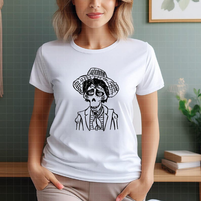 Puede incluir: Camiseta blanca con una ilustraci&oacute;n en blanco y negro de un personaje de la pel&iacute;cula "Coco". El personaje lleva sombrero, chaqueta y corbata. El dise&ntilde;o est&aacute; centrado en la parte delantera de la camiseta.