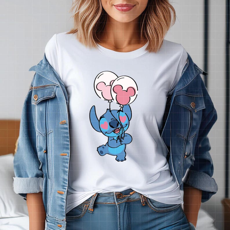 Pu&ograve; includere: Maglietta bianca con un personaggio dei cartoni animati, Stitch, che tiene due palloncini con le orecchie di Topolino. Il personaggio &egrave; blu con accenti rosa. I palloncini sono bianchi e rosa. La maglietta &egrave; indossata con una giacca di jeans.