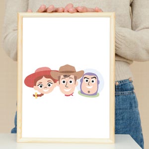 May include: A framed print featuring a minimalist cartoon illustration of three characters. From left to right, the characters include a person with a red hat and brown hair, a person wearing a brown cowboy hat, and a purple and white space character.