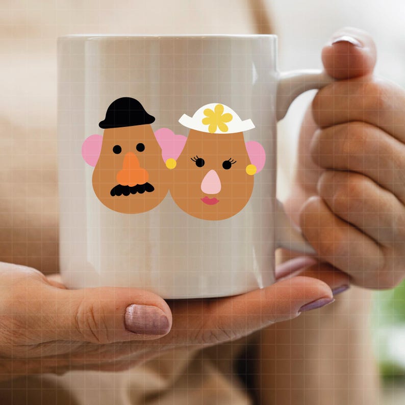 May include: A white ceramic mug featuring a graphic illustration of two potato-shaped characters. The left character wears a black hat and has a mustache, while the right character wears a white hat with a yellow flower and has pink lips.