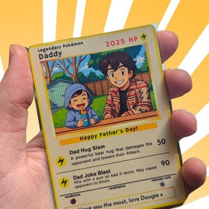 Pode incluir: Um cart&atilde;o Pok&eacute;mon Lend&aacute;rio com uma ilustra&ccedil;&atilde;o de desenho animado de um pai e filho, com o texto "Happy Father's Day!". O cart&atilde;o diz "Daddy" e inclui descri&ccedil;&otilde;es de ataque. O cart&atilde;o &eacute; mantido em uma manga protetora.