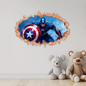 May include: A wall decal featuring Captain America bursting through a brick wall. The superhero is in a dynamic pose, holding his shield. The shield is red, white, and blue with a star. The decal is set against a blue sky background.