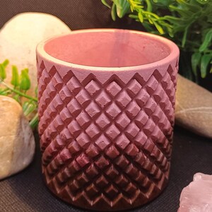Peut inclure: Un pot de fleurs en béton avec un motif en diamant, dégradé de rose à brun. Le pot a une finition lisse.