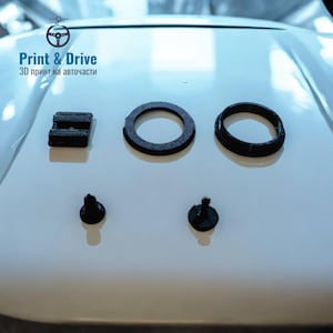 May include: Black 3D-printed automotive parts, including rings, a rectangular piece, and small, rounded components. The parts are arranged on a white surface. The image includes the text "Print & Drive" and "3D print on auto parts."