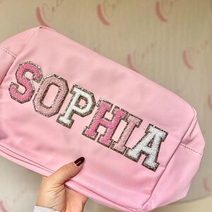 May include: Pink zippered pouch with the name "SOPHIA" in sparkly pink, white, and gold letters.