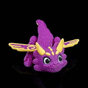 May include: A purple dragon figure with yellow horns and wings. The dragon has large black and white eyes and a textured body. The wings have a yellow and purple swirl design. The figure is set against a black background.