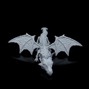May include: A gray dragon figurine with outstretched wings. The dragon has detailed scales and textured wings. The figurine is set against a black background, highlighting its form. The dragon's head is facing forward, with visible horns and eyes.