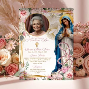 May include: A memorial card with a photo of a woman, floral accents, and text in Spanish. The card features an image of the Virgin Mary and a rosary. Pink and white roses and pampas grass surround the card.