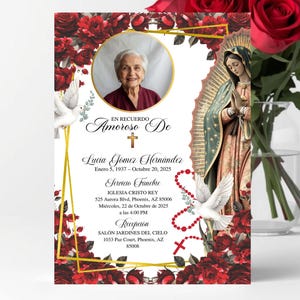 May include: A memorial card with a photo of a woman, surrounded by red roses and floral designs. The card includes text in Spanish, a gold frame, and an image of the Virgin Mary. A bouquet of red roses is in a glass vase.