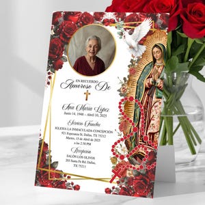 May include: A memorial card featuring a portrait of a woman, adorned with red roses and religious imagery. The card includes text in Spanish, a gold frame, and a depiction of the Virgin Mary. A bouquet of red roses is in the background.