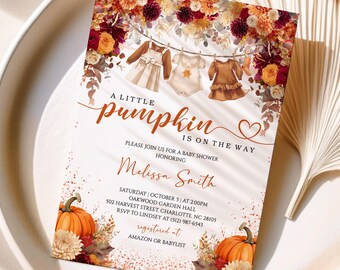 May include: Baby shower invitation with floral and pumpkin accents. The invitation features the text "A Little Pumpkin is on the Way" and details for Melissa Smith's baby shower. The design includes illustrations of baby clothes hanging on a clothesline.